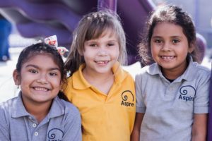 Three female Aspire students smiling at the camera