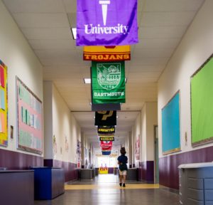 Aspire student walking down the hallway with flags hanging from the ceiling