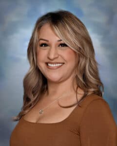 Headshot of Jessica Aguilar wearing a rust shirt against a blue background