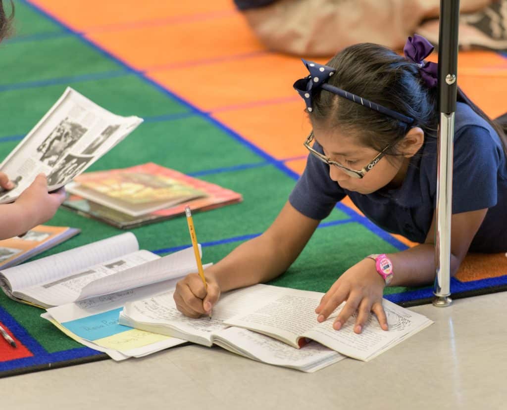 Aspire scholar reading and writing within her workbook.