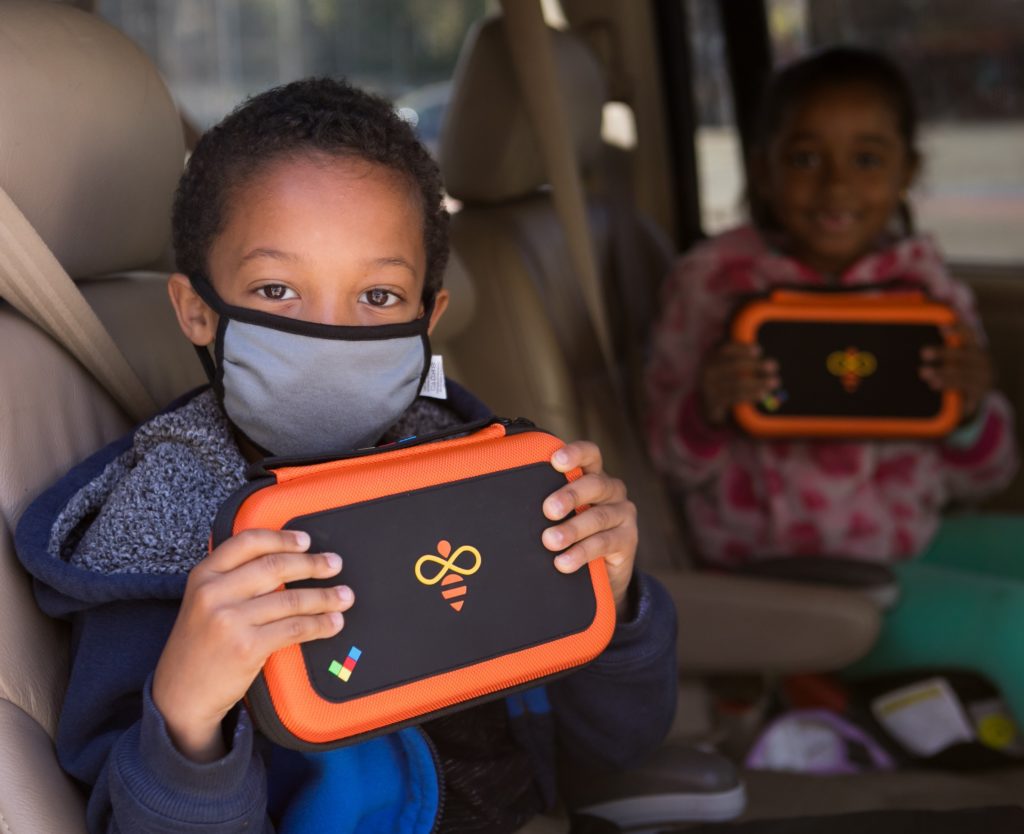 Two Aspire students in car holding up onetab devices they recieved for free!