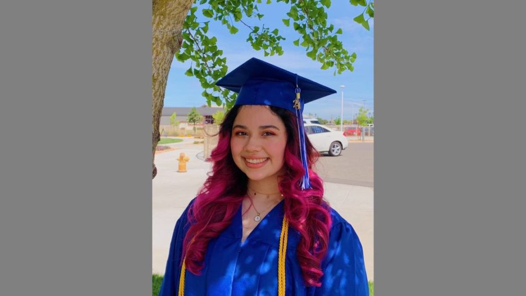 Scholar in cap and gown outside Modesto Junior College.