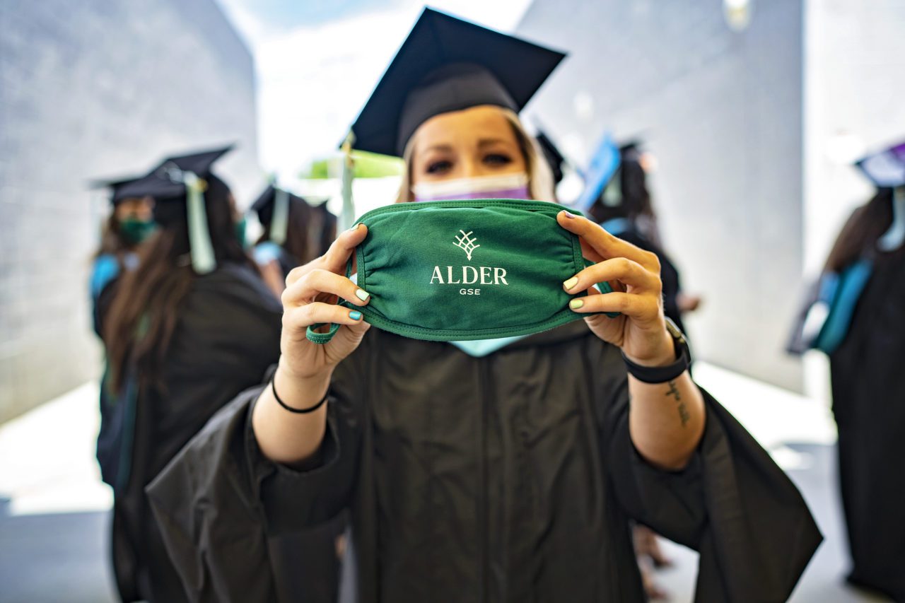 Alder 2021 Graduation Ceremony Grad holding mask with Alder logo embellished