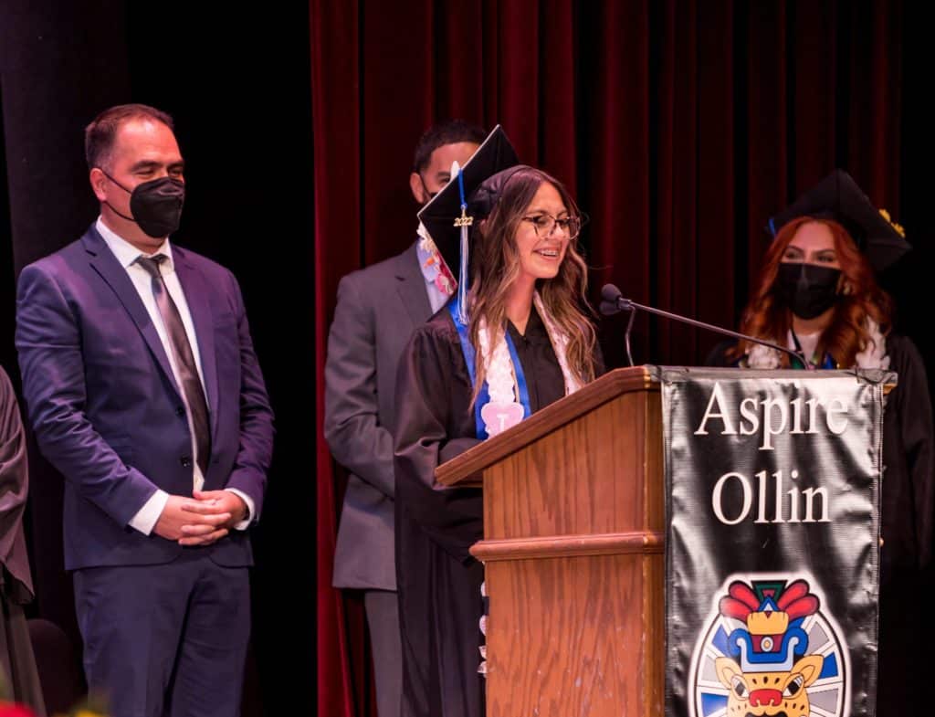 Joel Ramirez (back left) listens as a student speaks at a graduation ceremony.
