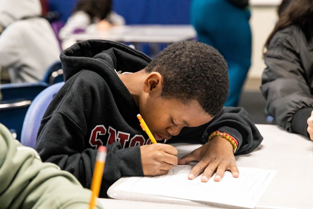 A young male student in class working on a assignment in Oakland, CA.