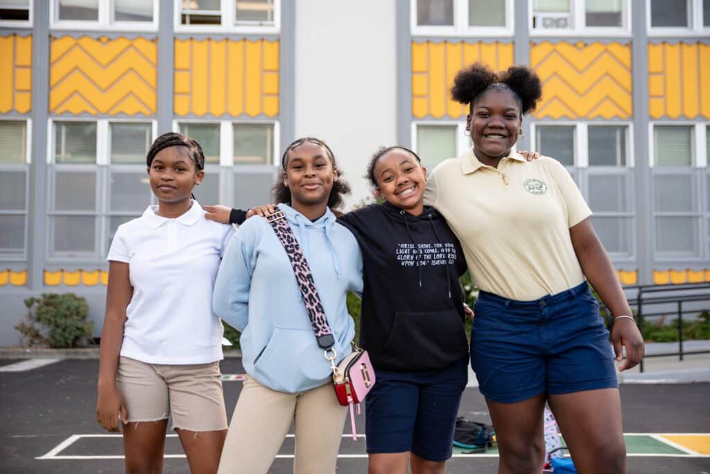 Aspire Berkley Academy scholars smile together outside of school building.